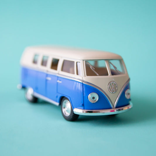 On a blue background is a blue and white VW bus toy.