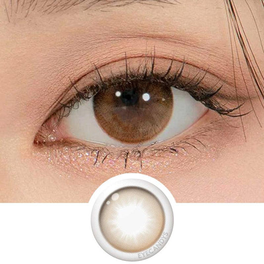Macro shot of an eye wearing the DooNoon Glam 1-Day Brown (10pk) prescription colour contact lens, showing the multi-colored detail and natural effect on dark brown eyes, with clean eye makeup. At the bottom is the pattern of the colored lens design, showing the dotted detail and pigmentation.