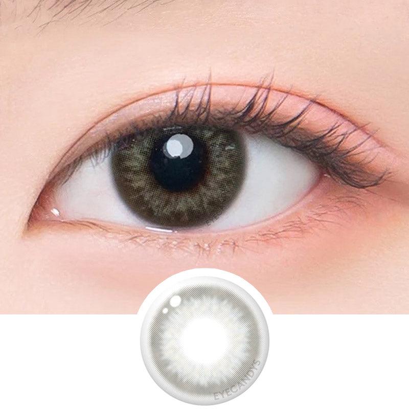 Macro shot of an eye wearing the DooNoon Rona 1-Day Grey (10pk) prescription colour contact lens, showing the multi-colored detail and natural effect on dark brown eyes, with clean eye makeup. At the bottom is the pattern of the colored lens design, showing the dotted detail and pigmentation.
